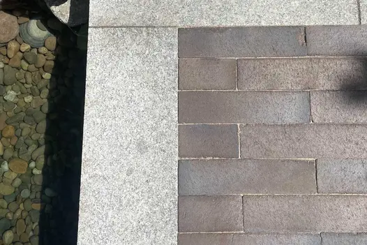 Chelsea clay pavers with sanded joints laid with plank paving edge above pond with pebbled bottom. Built by Big Fish Landscapes.