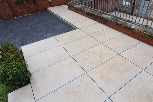Raised garden terrace paved with Limestone imitation Porcelain paving sitting alongside dark blue Clay Paving bricks.