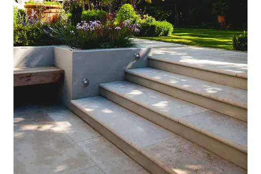 4 Jura Beige smooth limestone bullnose steps rise past flanking wall with 2 inset lights to path past lawn and beds.