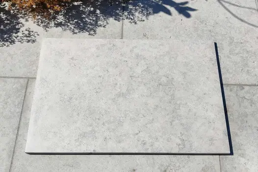 900x600 Jura grey Porcelain slab on top of a Jura Grey Limestone patio showing the difference between porcelain and real limestone.