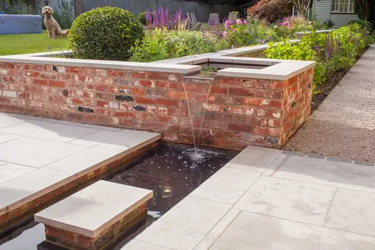 Water flows from raised pond into rill with stepping stone between pavements of Jura Grey Limestone. Design by Simon Orchard.