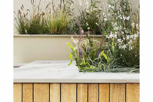 From paved area, steps rise between terraced, wood-clad beds topped with Jura Grey coping with 5mm chamfer profile.