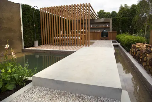Very large, thick Jura Grey sawn limestone slab forms bridge in path over pond to pergola-covered seating area.