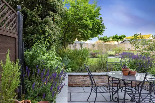 Kandla Grey Indian sandstone coping stones with rock-faced profile top brick wall surrounding patio in matching paving.