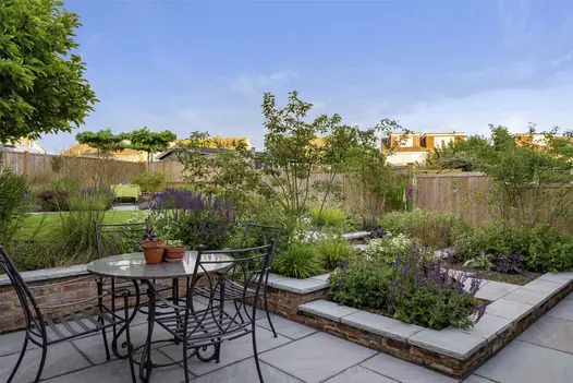 Kandla Grey Indian sandstone coping stones top low retaining brick walls of fully planted raised beds, rising in steps to lawn.