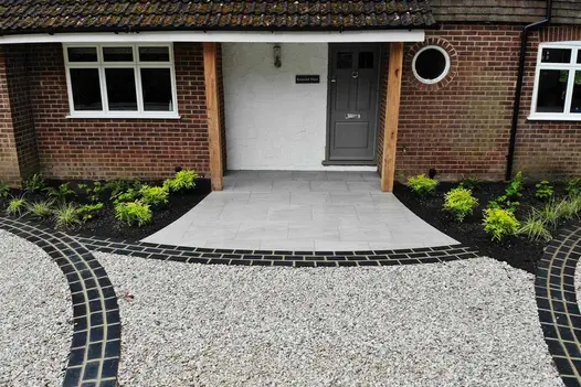 Front entrance shows kandla grey porcelain paving used alongside grey resin and black limestone setts in unique pattern.