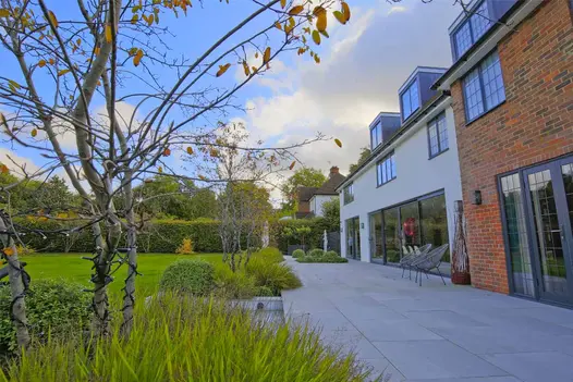 Seen from one end, Urban Grey Porcelain patio, by Karen McClure Garden Design, stretches across width of house, lawn on left.
