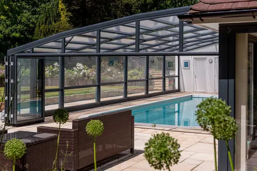 View from patio of Tumbled Mint sandstone paving through open bi-fold doors into glassed-in swimming pool area.