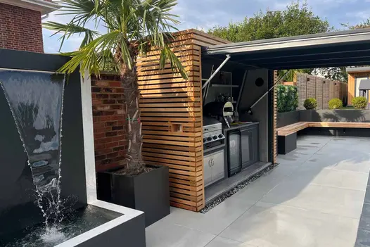 Patio of Yard porcelain paving with L-shaped bench and outdoor kitchen in cupboard with open up-and-over garage-door type front.