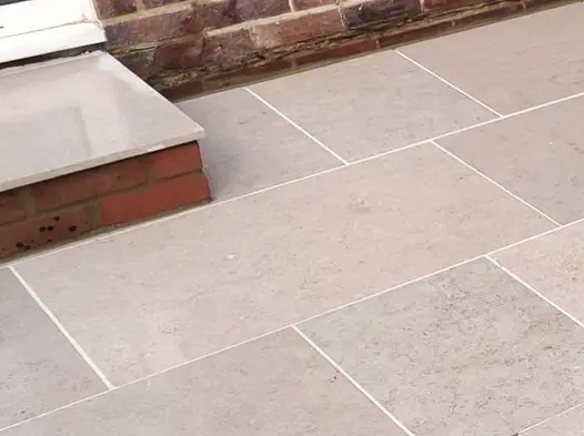 Shallow step with brick riser down from door 2 Egyptian beige limestone paving with white joints. Laid by Kiwi Landscapes.