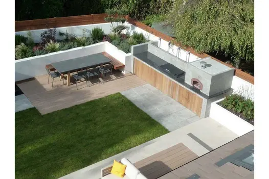 Birds eye view of outdoor kitchen with mocha designboard composie decking used for hosting the dining table, lawn area adjacent.
