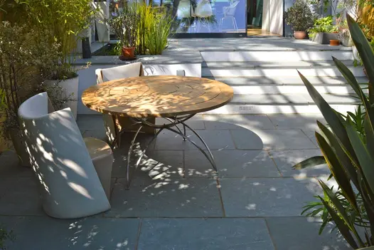 Kota Blue limestone patio on 2 levels separated by 4 steps with matching treads and white risers. Round table in foreground.