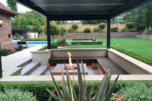Sunken seating area with Coppered Oak Millboard decking bench surrounding central firepit on 3 sides. By Landscape Design Studio.