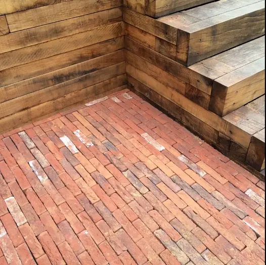 Wooden steps next to a large area of Romsey Antique Clay Pavers that show off the colour variation and brick texture.
