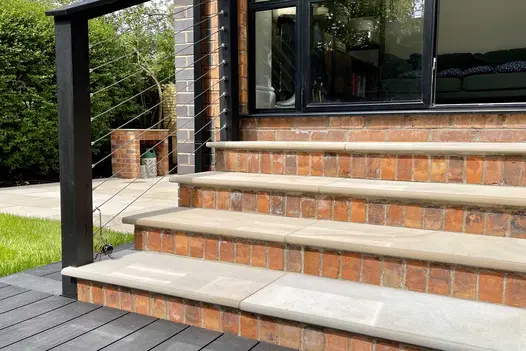 4 brick steps with Light Buff sawn sandstone treads rise to modern double doors from decking area in back garden.