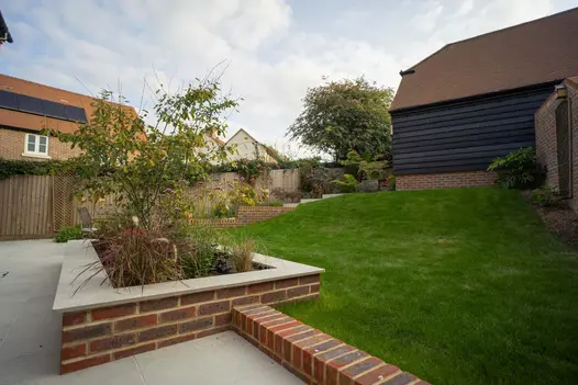 Light Grey Porcelain used on a patio floor and on matching wall coping stones and combined with red brick walls.