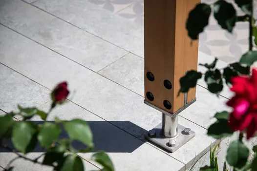 Close view of steel foot of wooden post attached with bolts into Light Grey porcelain plank paving. Built by Timeless Landscapes.