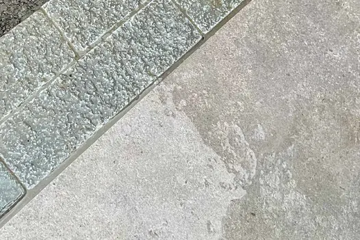 Wet Antique Grey stone pavers form a seamless border around a patio slab, seamlessly integrating into the surrounding landscape.