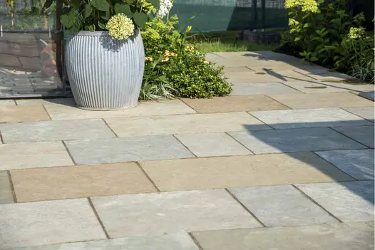 Mix of Kota Brown limestone slab sizes laid running bond with hydrangea in fluted pot and planted borders.