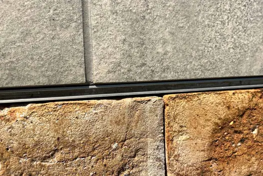 Slot drain seen in the middle of London Mixture Clay Paver Bricks and grey porcelain, showing colour variations and texture.