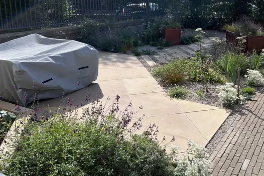 Buff smooth sandstone paving cut to fit around beds, gravel and slab path and clay paved area. Design by Mags Wright.
