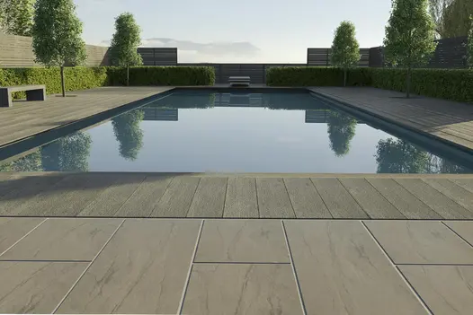 Swimming pool terrace edged with low hedges. Paved surround of Marble Grey outdoor vitrified tiles and composite decking.