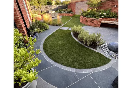 Small but impressive back garden using Charcoal Porcelain Paving in curved feature with grass and planting in between.