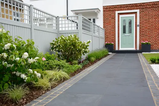 Midnight Black limestone paving path, edged with matching sets, slopes up to front door past planted border. Design by Tom Howard.