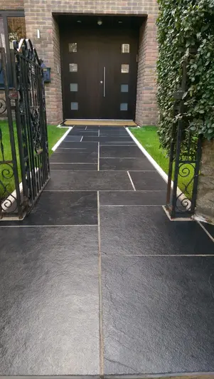 White-edged path of Midnight Black limestone slabs, treated with colour-enhancing sealant, leads to large front door.
