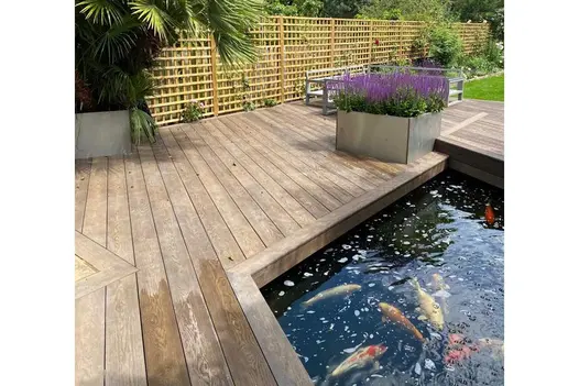 Steel lavender trough sits on Millboard Antique Oak decking between sunken goldfish pond and trellis fencing. By Shoots and Leaves.