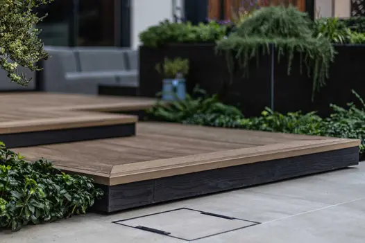 Close up of corner of golden oak millboard decking step with profiled edge and darker shade fascias.