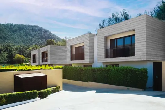 Modern building clad in Smoked Oak Millboard Shadow Line composite cladding, surrounded by hedges and set against a backdrop of hills.