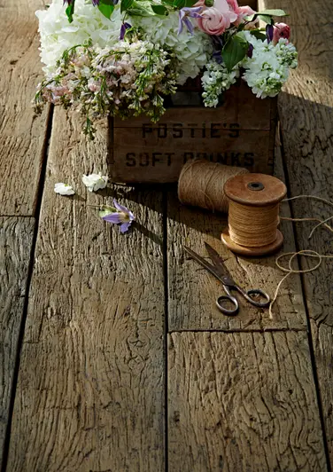 Close-up of Vintage Millboard Decking with sewing equipment and a plant box, highlighting the detailed grain and rustic charm of the aged wood finish.