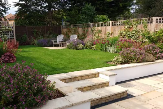 Rendered white wall leading to raised lawn capped by mint indian sandstone coping stones with matching paving and steps.