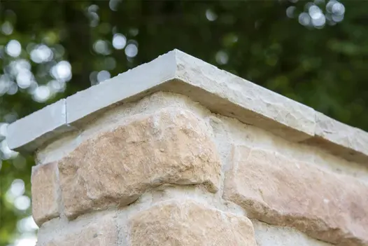 Close up of corner of mint indian sandstone coping stone shows rock-faced profile and hand-cut edges.