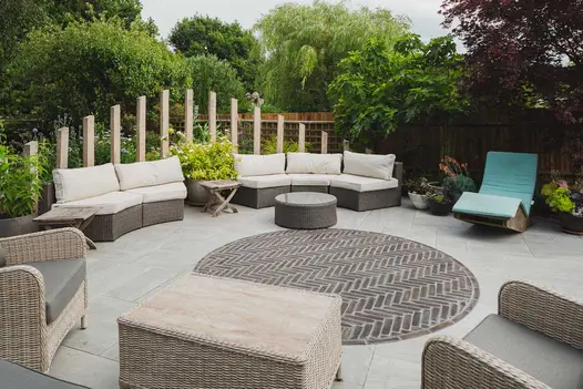 Circle of Moderna brick paving laid herringbone in centre of Kandla Grey porcelain patio edged with posts graduated in size.