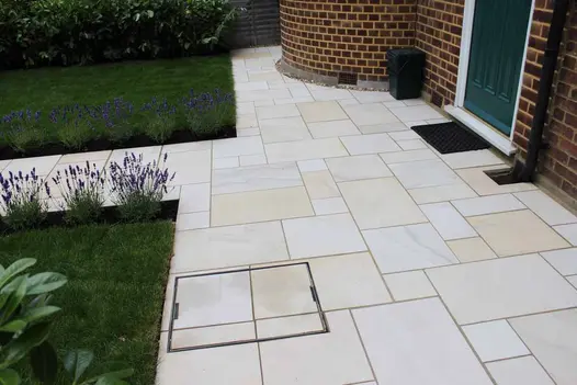 Straight path leads to Multi Mint smooth paving slabs laid across house frontage with doormat below front door.