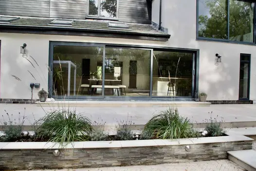 Huge french doors on white house lead onto ash beige porcelain patio using matching steps and 20mm bullnose copings.