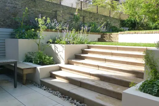 Pebble drainage channel at base of 7 Jura Beige sawn sandstone bullnose steps rising from matching paving to lawn.