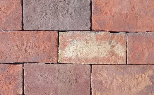 Close-up of Old English clay paver bricks laid in stretcher bond pattern without sanded joints, showing grey, white and pink tones.