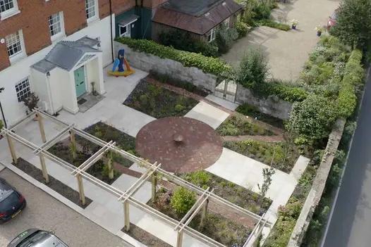 Aerial view of garden with 4 large beds separated by wide white paths, set around central circle of Old English Clay Pavers.