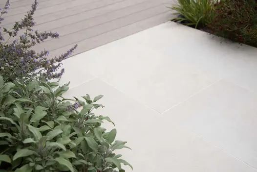 Slab Khaki Porcelain path with planted flower beds on both sides joining up with a mocha coloured composite deck.