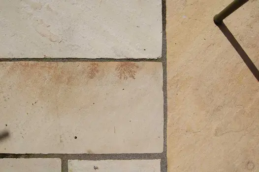 Close overhead view of project pack Tumbled Mint sandstone paving slabs, with wide joints, showing cream and yellow colours.