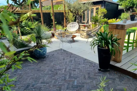 Garden by Paul Slater, paved with clay pavers and Beige Smooth sandstone paving, with studio, exotic potted plants and palm trees.