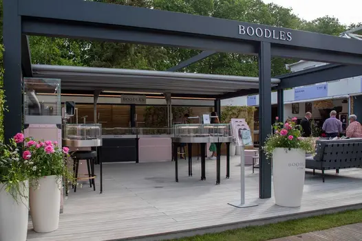 Luna DesignBoard Pencil round boards edge RHS Chelsea trade stand. Planted pots and jewellery displays stand on matching decking. 