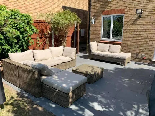 Platinum Grey Porcelain Paving Slabs in small garden for entertaining with rattan couches and table. Garden Tiles UK with free delivery.
