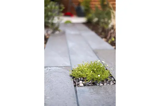 Close-up of Platinum Grey Porcelain Planks, showcasing their texture, with moss and gravel thoughtfully placed between them.