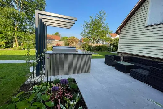 Outdoor kitchen bar and dining area with a porcelain patio and path leading back towards the property.