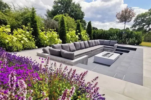 Slab Coke porcelain downstand steps down to sunken seating area with firepit and long sofa. Design by Bancroft Lee Landscapes.