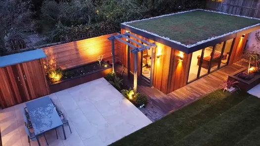 Elevated view of a rear garden featuring, office building, porcelain patio, raised flower beds and cedar screening.